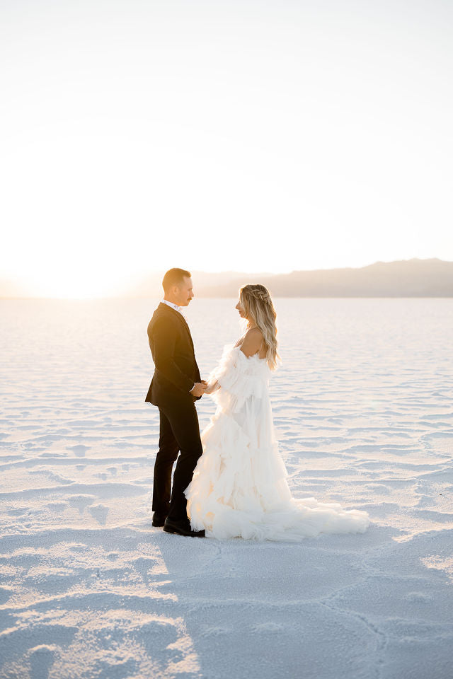 Engagement session at the Salt Flats in Utah holding hands walking on the Salt Flats during golden hour at sunset